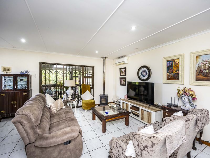 A comfortable living room featuring tiled flooring, a freestanding fireplace, and a split-system air conditioner, with direct access to an outdoor area via a security gate.