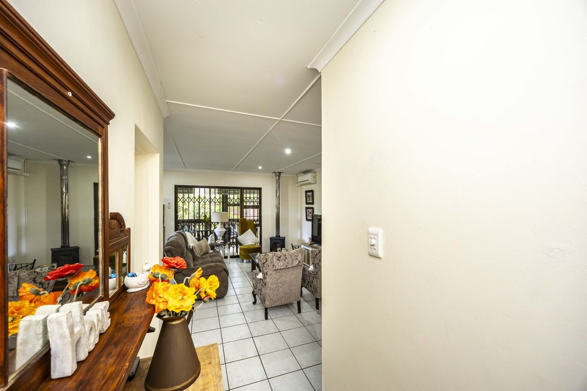 A bright living area featuring tiled flooring, a wood-burning stove, and a split-system air conditioner, leading out to a secure patio area.