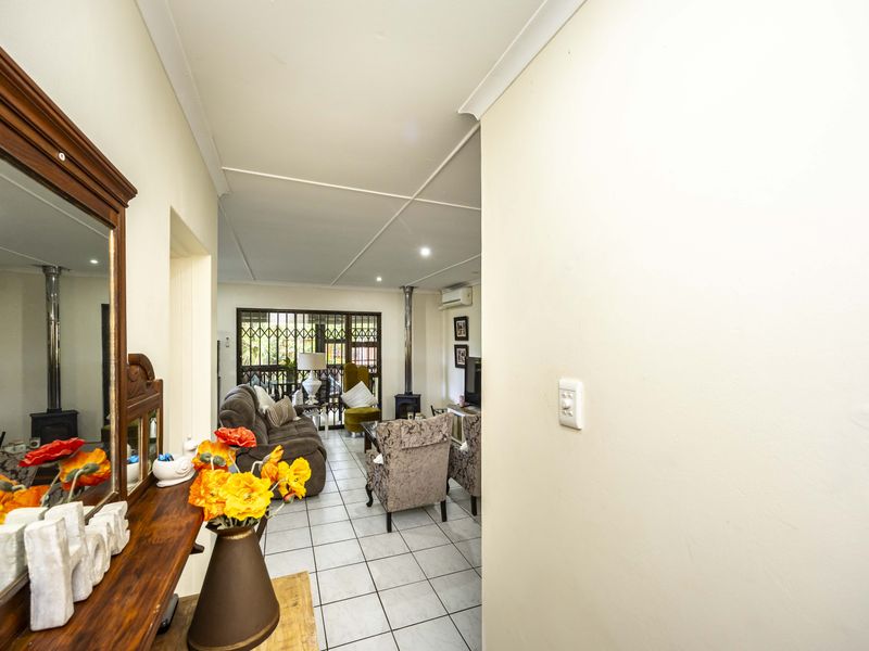 A bright living area featuring tiled flooring, a wood-burning stove, and a split-system air conditioner, leading out to a secure patio area.