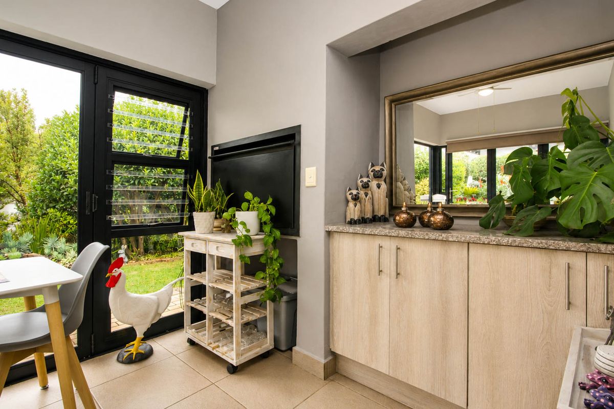 A bright living area featuring built-in cabinetry with stone countertops, a fireplace, and direct access to the garden through glass doors.