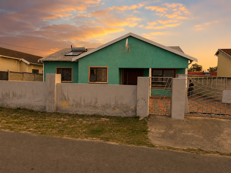 Front view of a detached house featuring a solar water heater, perimeter wall with gate, and security bars on windows.