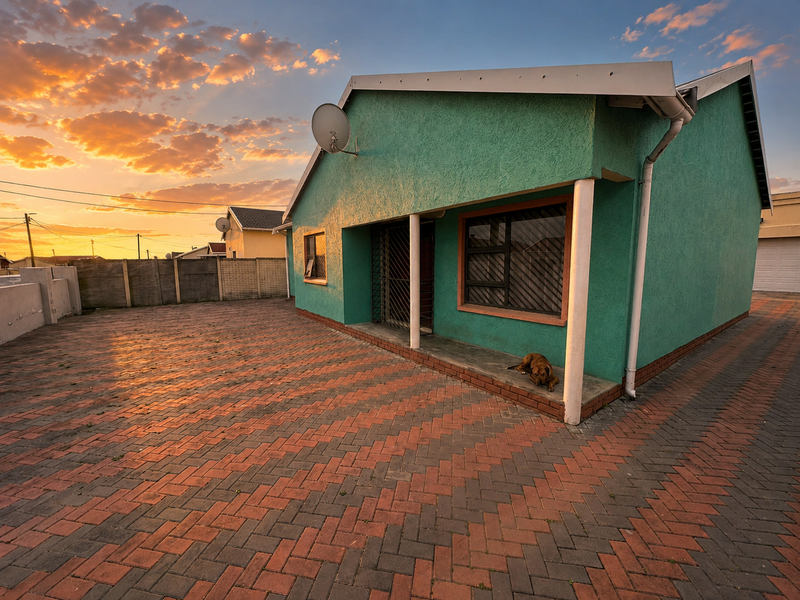 Front view of a house featuring a paved driveway, covered porch, and exterior wall with security gate and satellite dish.