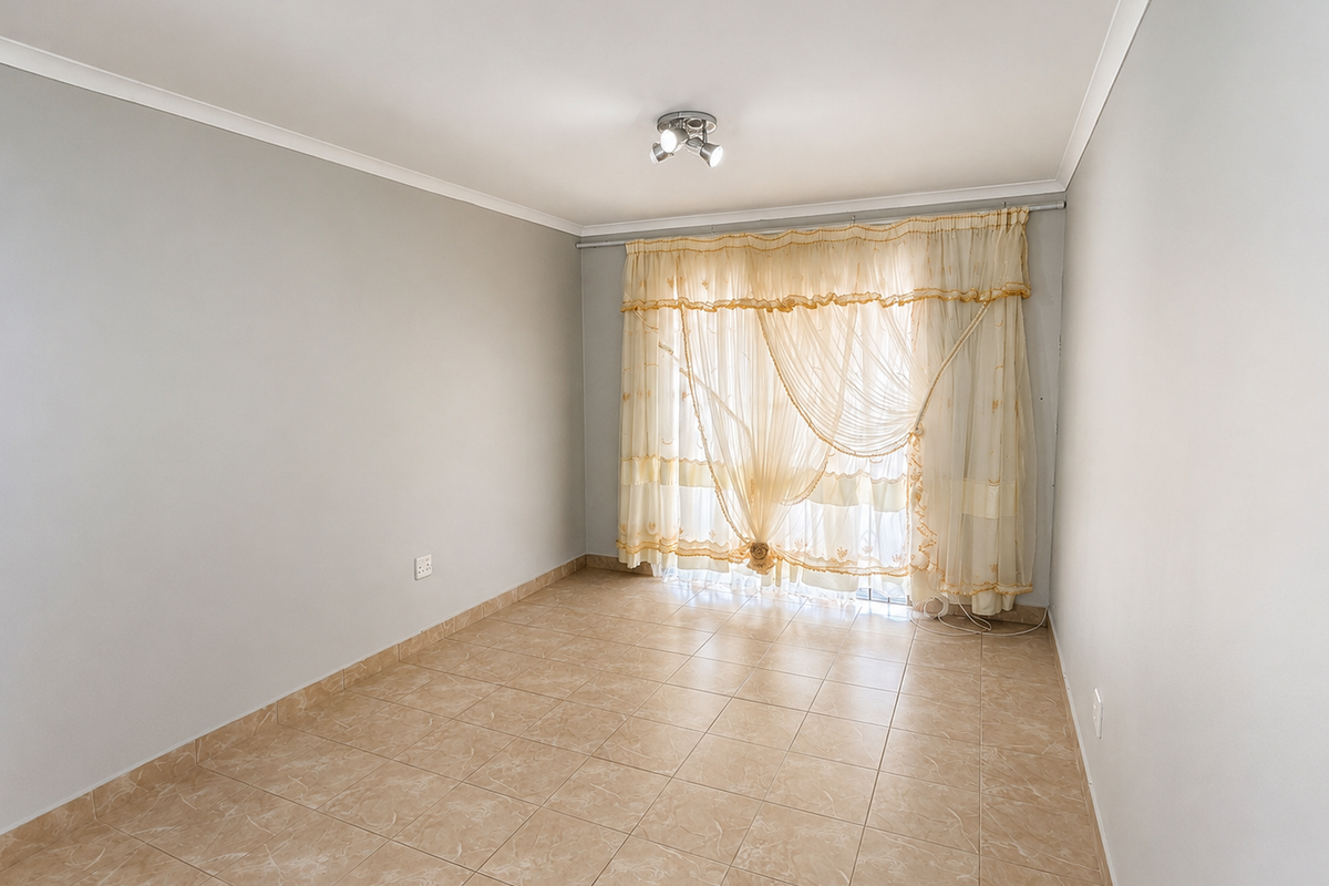A bright, empty bedroom featuring neutral wall paint, tiled flooring, and a ceiling-mounted light fixture, ready for personalization.