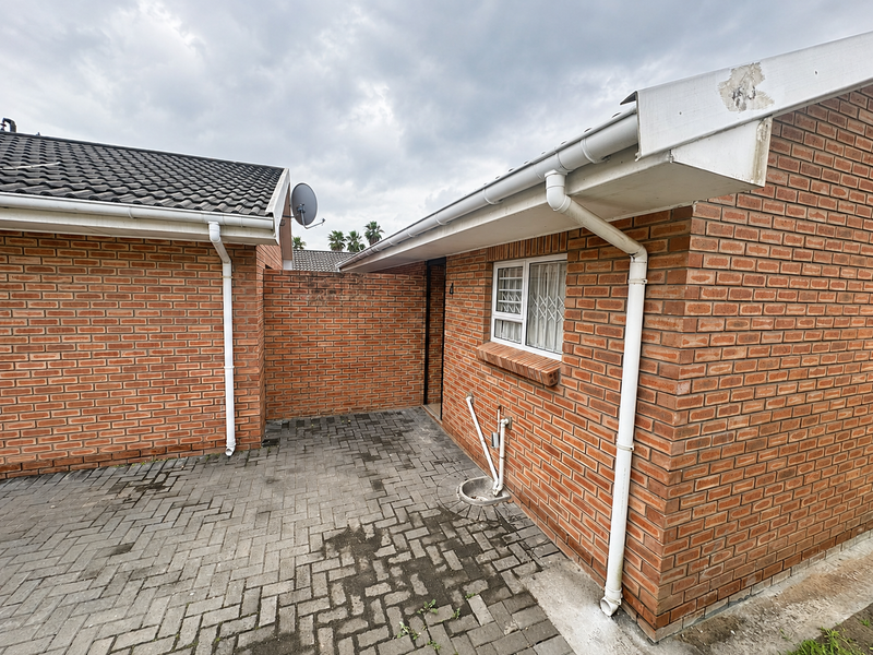 A rear courtyard area featuring brick exterior walls, paved flooring, and functional guttering systems, providing a private outdoor space for the townhouse.