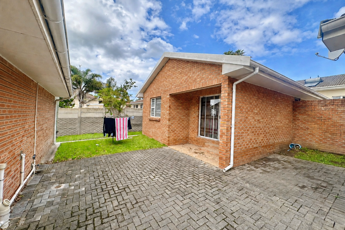 Rear view of the townhouse featuring a private paved courtyard, brick exterior walls, and secure window bars.