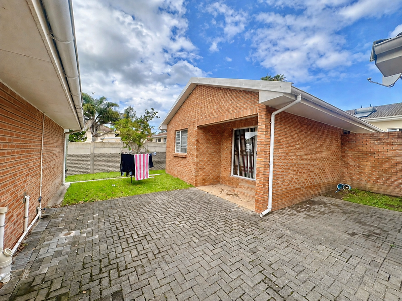 Rear view of the townhouse featuring a private paved courtyard, brick exterior walls, and secure window bars.