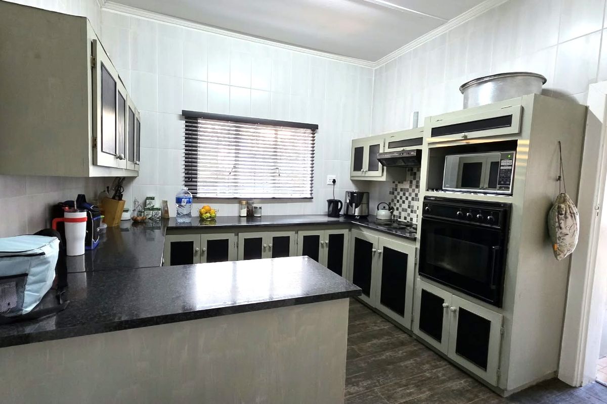A functional kitchen featuring built-in cabinetry, granite countertops, and integrated appliances including an oven, microwave, and extractor fan.