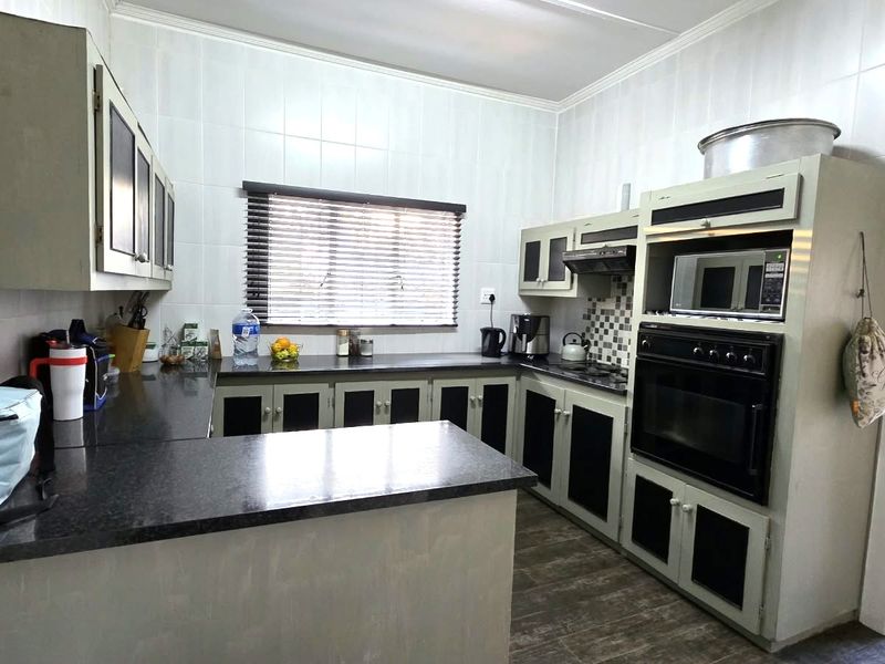 A functional kitchen featuring built-in cabinetry, granite countertops, and integrated appliances including an oven, microwave, and extractor fan.