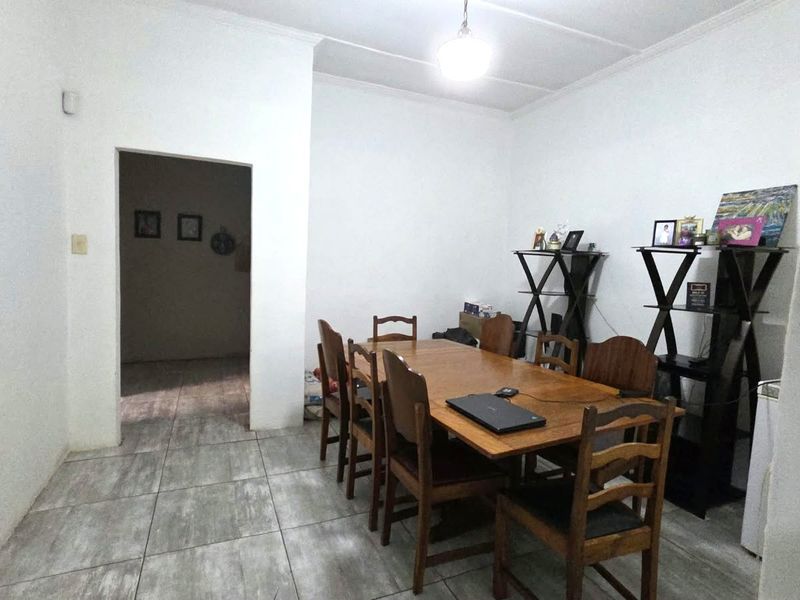 A simple dining room featuring tiled flooring and neutral walls, providing a functional space for family meals.
