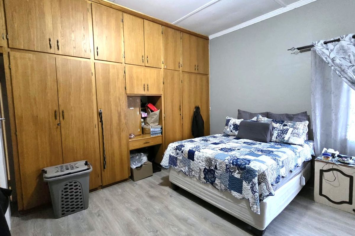 A bedroom featuring extensive floor-to-ceiling built-in wooden cabinetry, laminate flooring, and a coved ceiling.