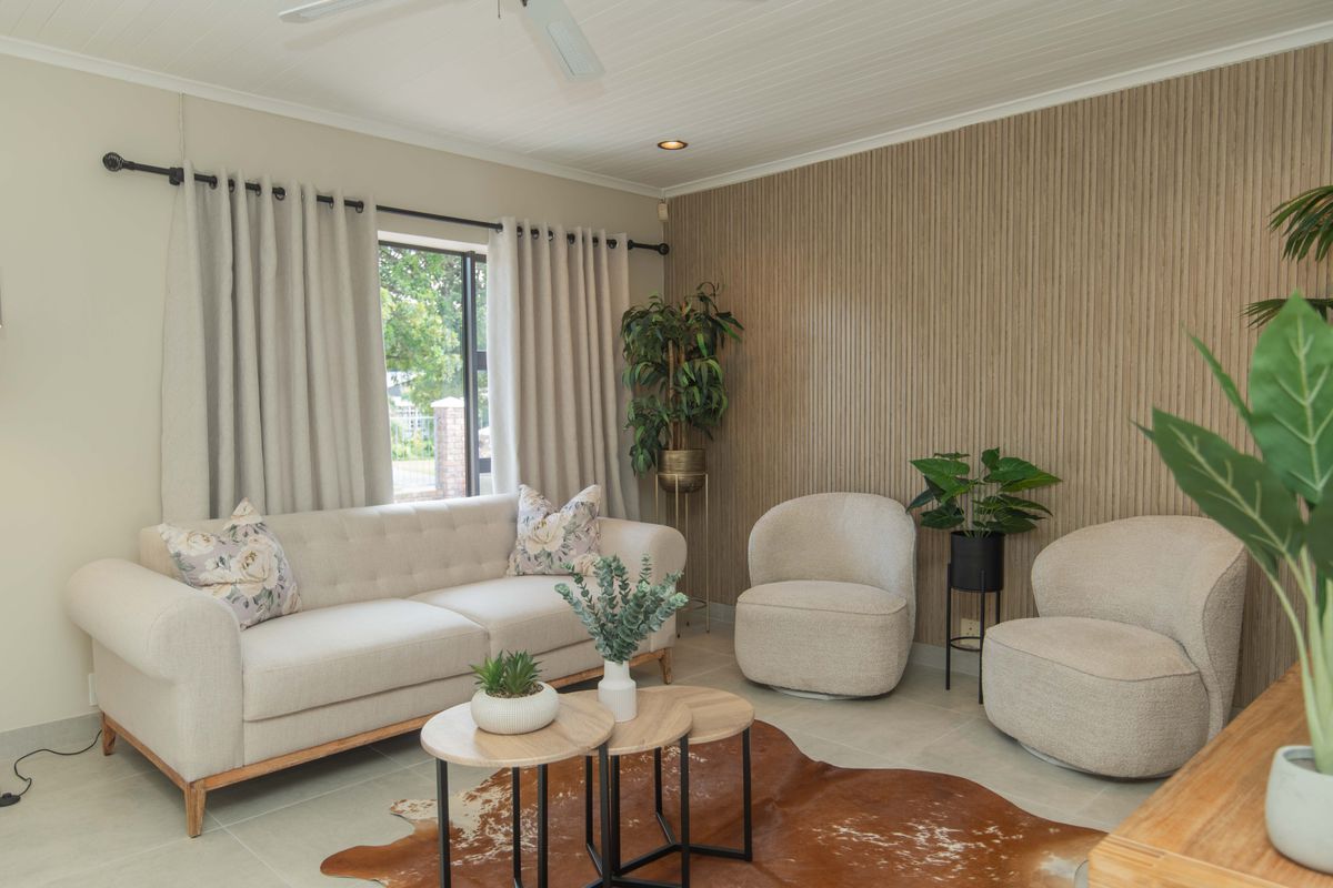 A well-maintained living room featuring a modern timber slat accent wall, tongue and groove ceiling, and neutral tiled flooring.