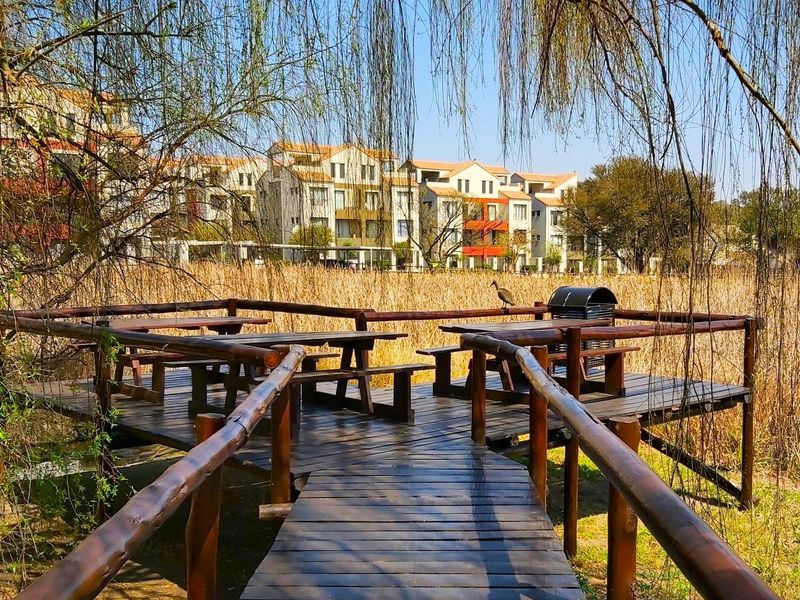 A wooden deck and walkway overlooking a natural wetland area with apartment buildings in the background.