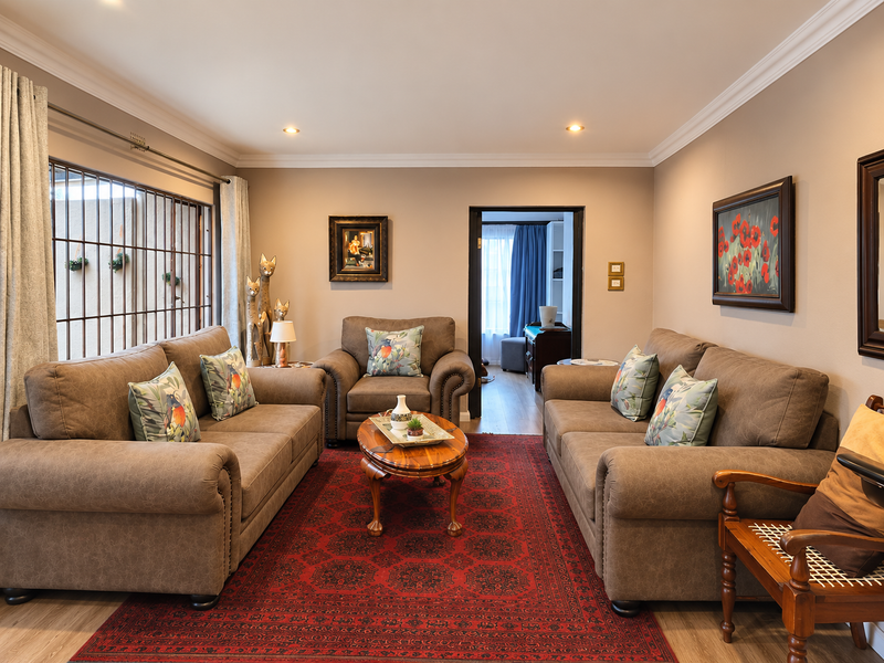 A well-maintained living room featuring recessed downlights, crown molding, and laminate flooring, with a view through to an adjacent room.
