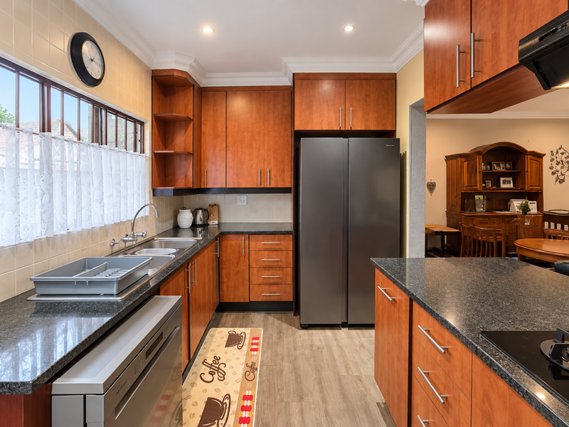A well-maintained kitchen featuring cherry wood cabinetry, granite countertops, integrated appliances, and a tiled backsplash, offering a functional and classic cooking space.
