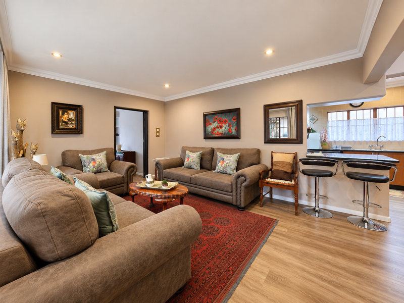 Spacious open-plan living area featuring laminate flooring, recessed lighting, and a breakfast bar connecting to the kitchen.