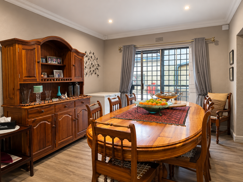 A well-maintained dining room featuring laminate flooring, crown molding, recessed lighting, and a sliding glass door providing access to the exterior.