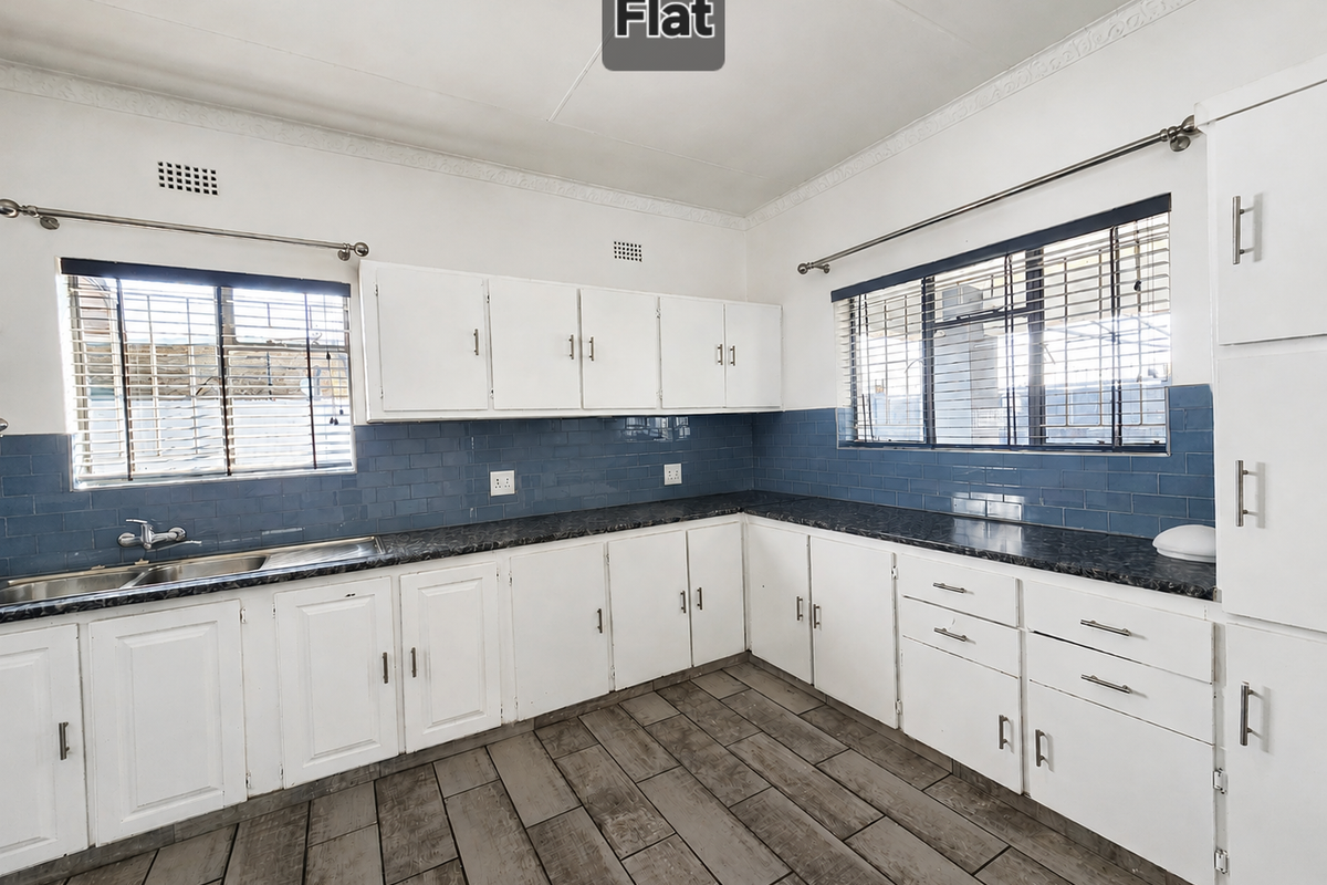 A functional kitchen featuring white built-in cabinetry, dark laminate countertops, blue tiled backsplash, and wood-look tiled flooring.