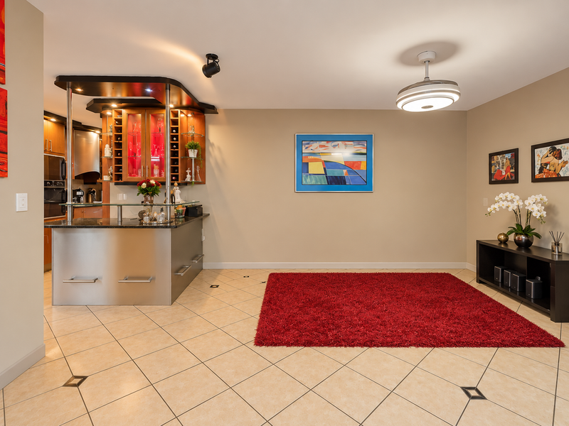 A well-maintained home bar area featuring a built-in counter with integrated cabinetry, tiled flooring, and modern ceiling lighting.