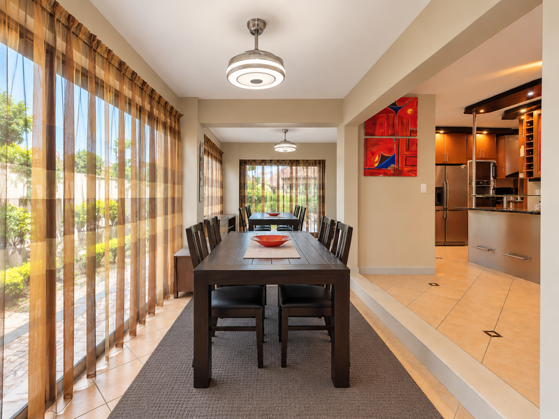 An open-plan dining and kitchen area featuring tiled floors, modern cabinetry, and large sliding glass doors that provide ample natural light.