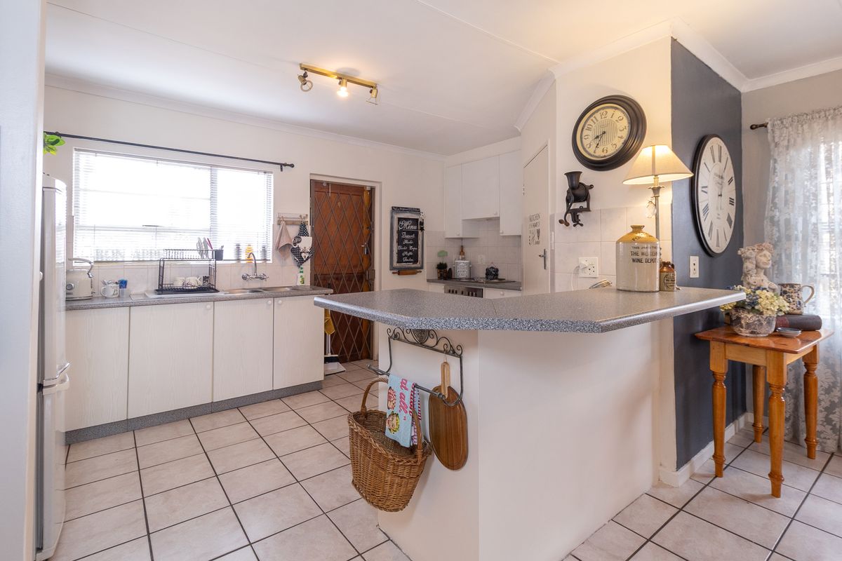Functional kitchen featuring white cabinetry, laminate countertops, a breakfast bar, and tiled flooring with direct access to an exterior security door.