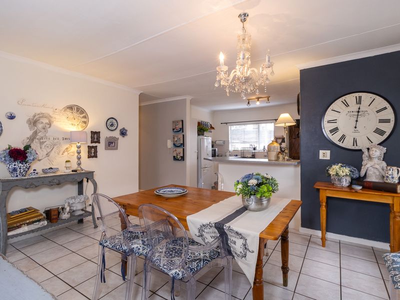 Open plan dining area featuring tiled flooring and a breakfast bar connecting to the kitchen, illuminated by a decorative chandelier.
