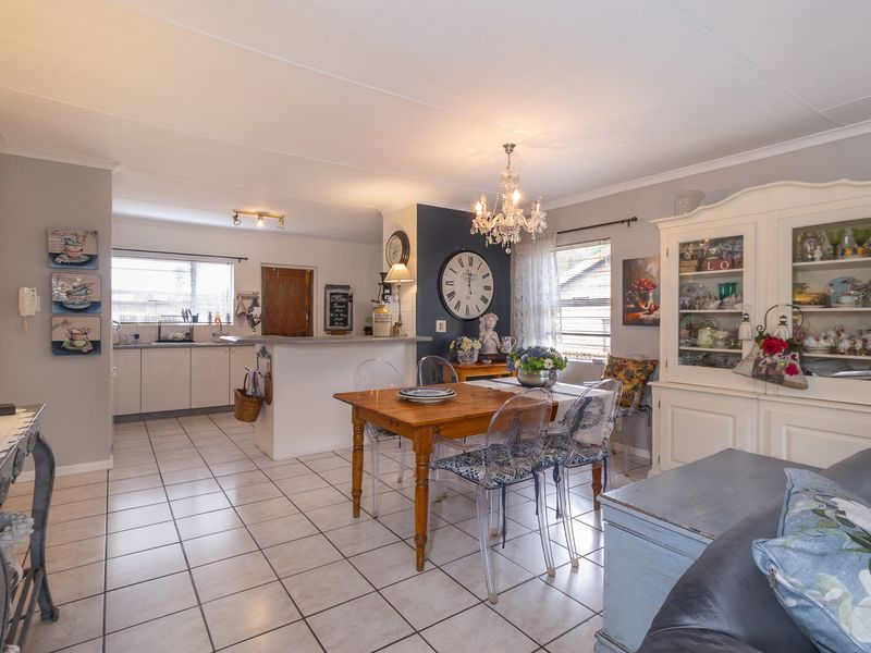 Open-plan living and dining area featuring tiled flooring, a breakfast bar, and a functional kitchen with ample cabinetry.