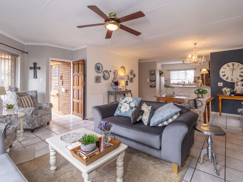 Open-plan living and dining area featuring tiled flooring, a ceiling fan, and an integrated kitchen space with direct access to the exterior.