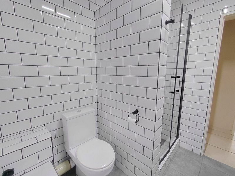 Modern bathroom featuring white subway tile walls, a walk-in shower with a glass screen, and a clean, minimalist layout.