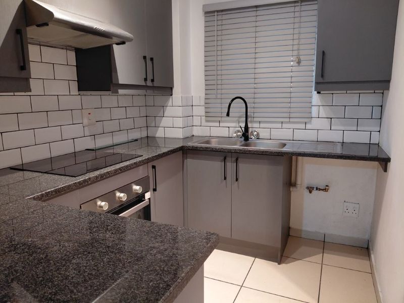 Modern kitchen featuring granite countertops, subway tile backsplash, built-in oven, electric hob, and a stainless steel double sink with a contemporary mixer tap.