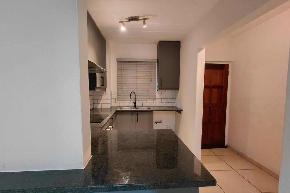 A clean, modern kitchen featuring granite countertops, subway tile backsplash, and dark cabinetry, offering a functional and well-maintained workspace.