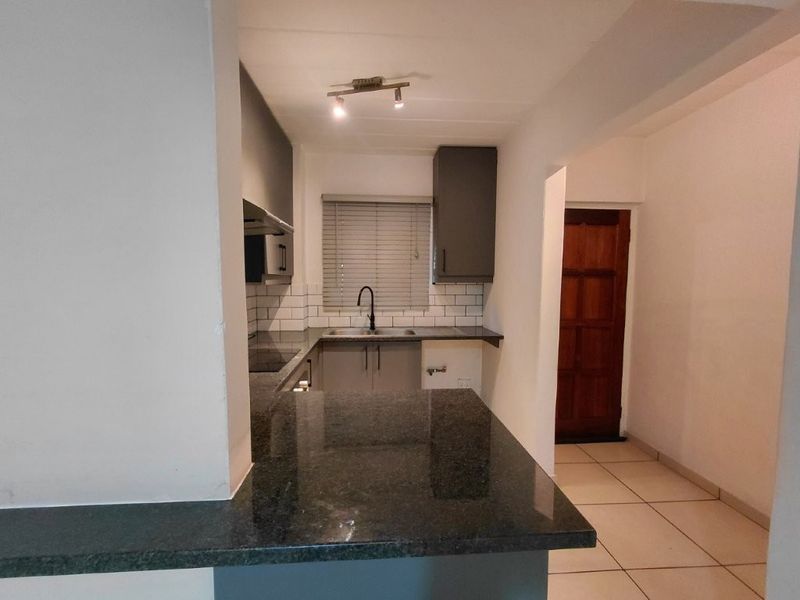 A clean, modern kitchen featuring granite countertops, subway tile backsplash, and dark cabinetry, offering a functional and well-maintained workspace.