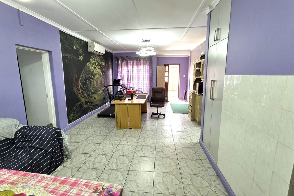 Spacious living area featuring tiled flooring, built-in storage cupboards, and a wall-mounted air conditioning unit, offering a versatile layout for various uses.