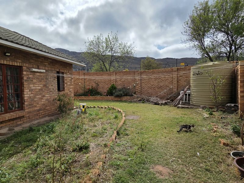 Rear garden area featuring a brick boundary wall, water storage tank, and established lawn space with potential for landscaping improvements.