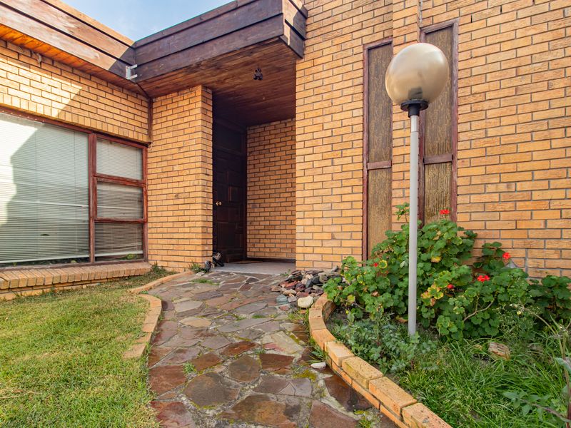 Front entrance of a face brick house featuring a stone paved walkway and timber eaves.