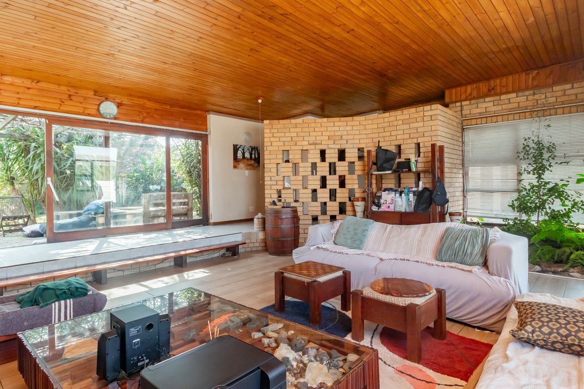 Spacious living area featuring a warm timber ceiling, exposed brickwork, and large sliding doors that provide seamless access to the outdoor patio and garden.