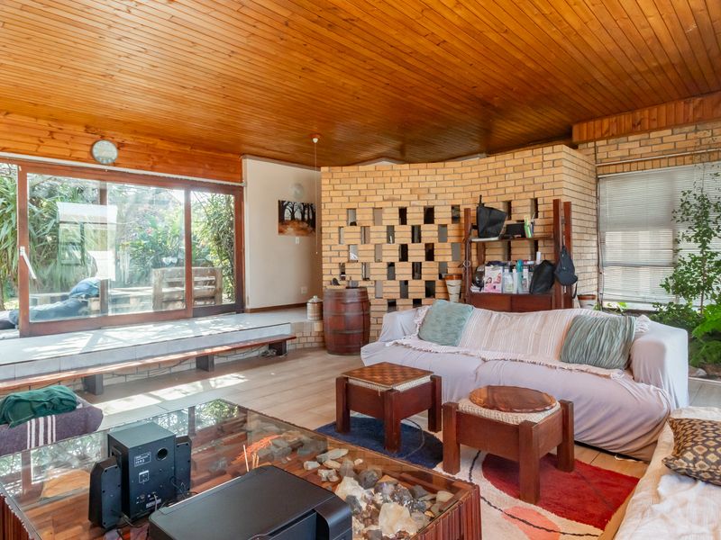 Spacious living area featuring a warm timber ceiling, exposed brickwork, and large sliding doors that provide seamless access to the outdoor patio and garden.