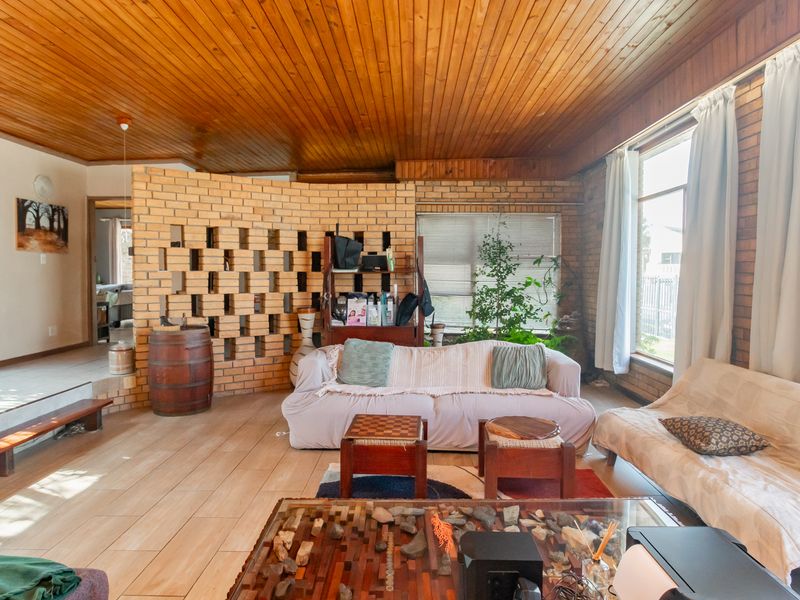 Spacious living area featuring a timber tongue and groove ceiling, exposed brick walls, and a unique breeze block partition, offering a rustic aesthetic.