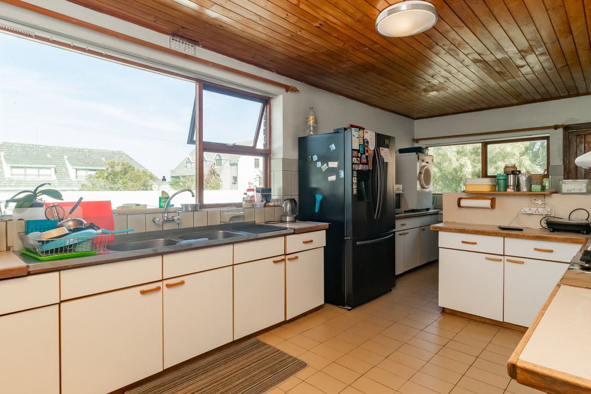 A functional kitchen featuring timber ceilings, tiled flooring, laminate countertops, and ample built-in cabinetry with a double basin sink.