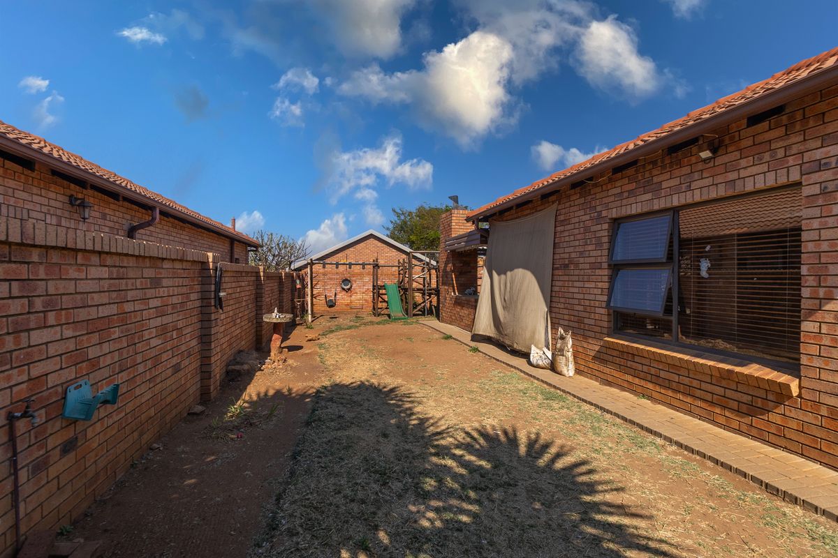 A private rear courtyard featuring face brick walls, a built-in braai area, and a low-maintenance garden space.