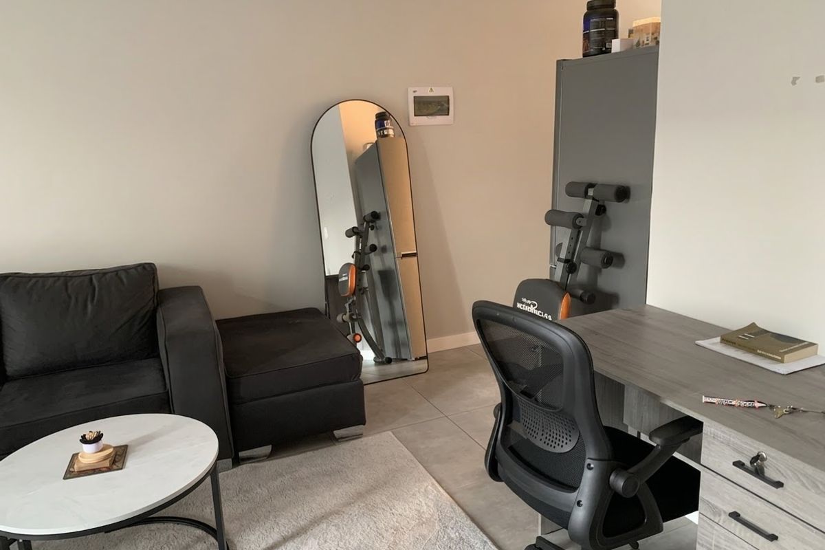 A functional living area featuring neutral wall tones and modern tiled flooring, currently utilized as a multi-purpose space.