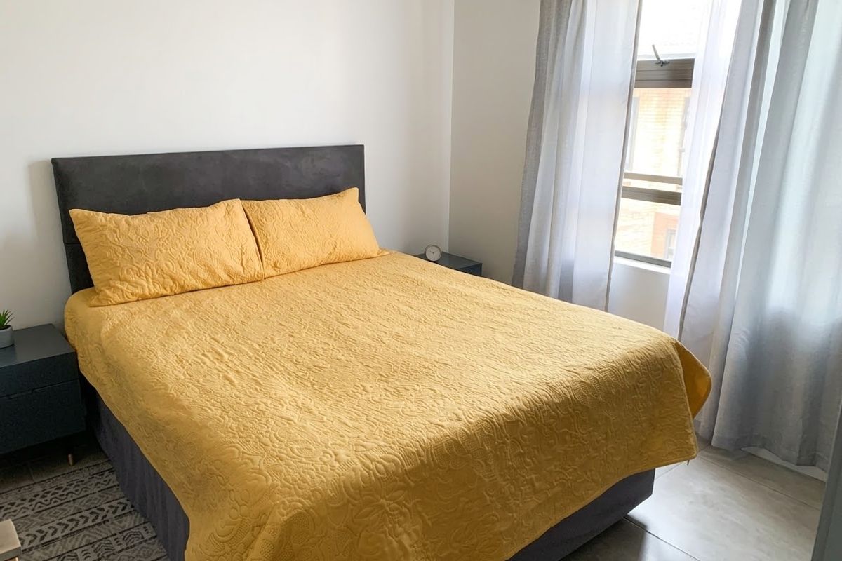A well-lit bedroom featuring neutral wall finishes, tiled flooring, and a window with natural light.