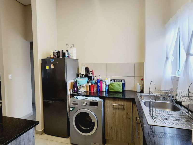 Functional kitchen area featuring granite countertops, double stainless steel sink, and built-in cabinetry with integrated space for laundry appliances.