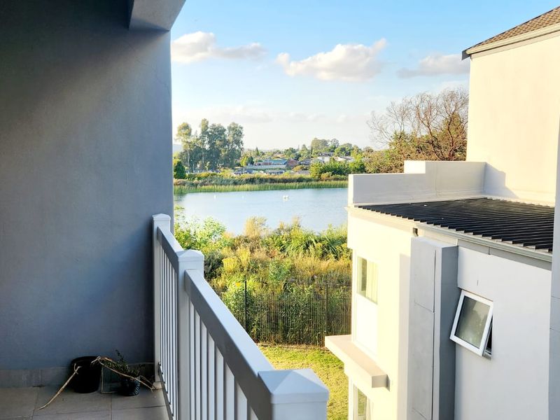 A private balcony offering scenic views of the surrounding landscape and nearby lake, featuring a clean balustrade and tiled flooring.