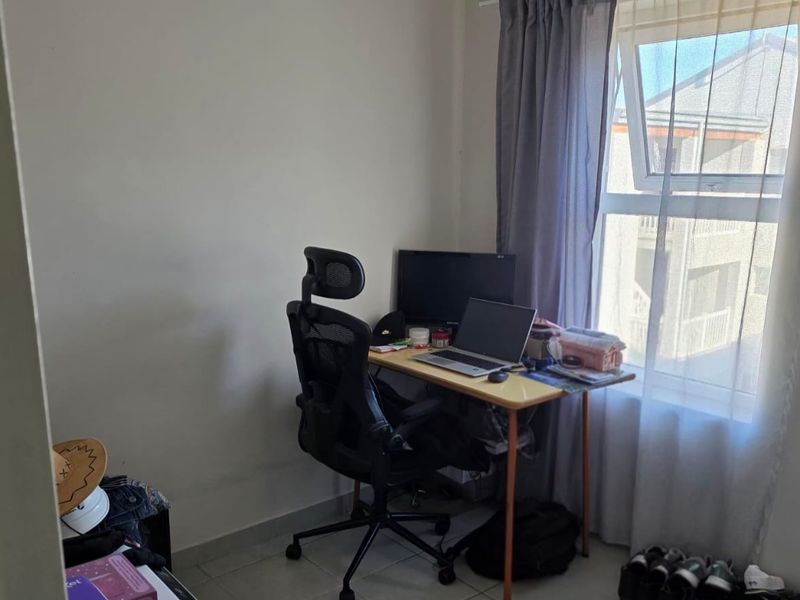 A functional home office space featuring tiled flooring and a large window providing natural light.