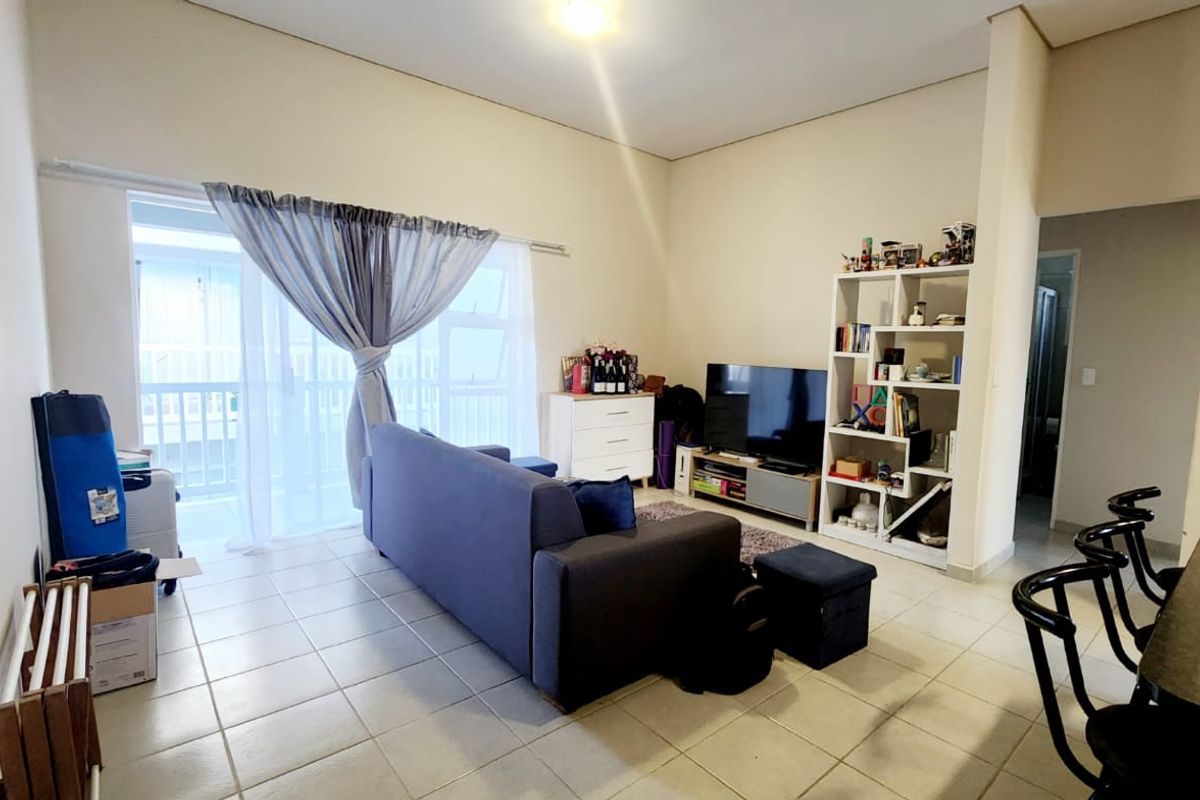 A living room featuring tiled flooring and a large sliding glass door providing access to an outdoor area.
