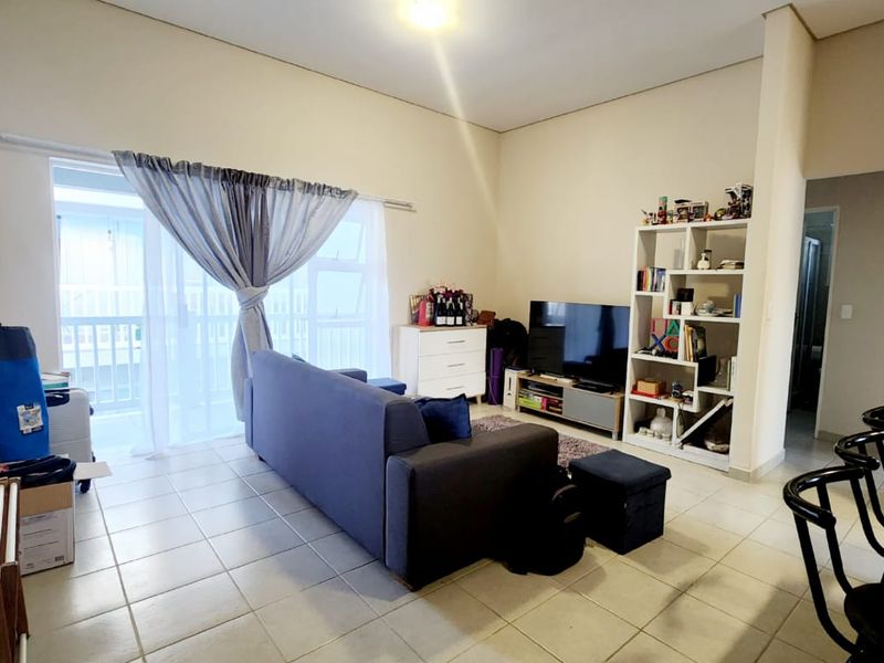 A living room featuring tiled flooring and a large sliding glass door providing access to an outdoor area.