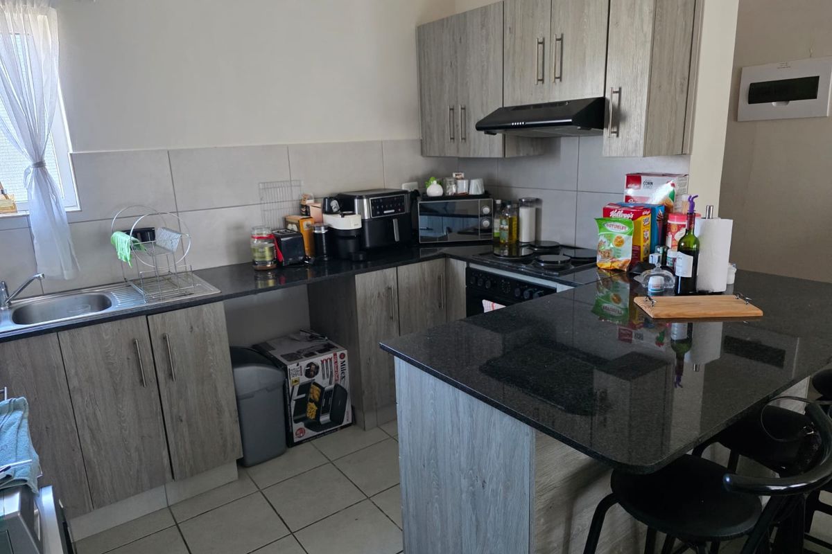 Modern kitchen featuring grey laminate cabinetry, granite countertops, a breakfast nook, and integrated appliances including an oven and extractor fan.