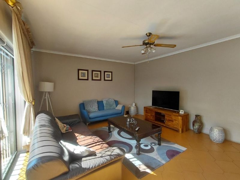 A comfortable living room featuring tiled flooring, a ceiling fan, and large sliding glass doors providing natural light.
