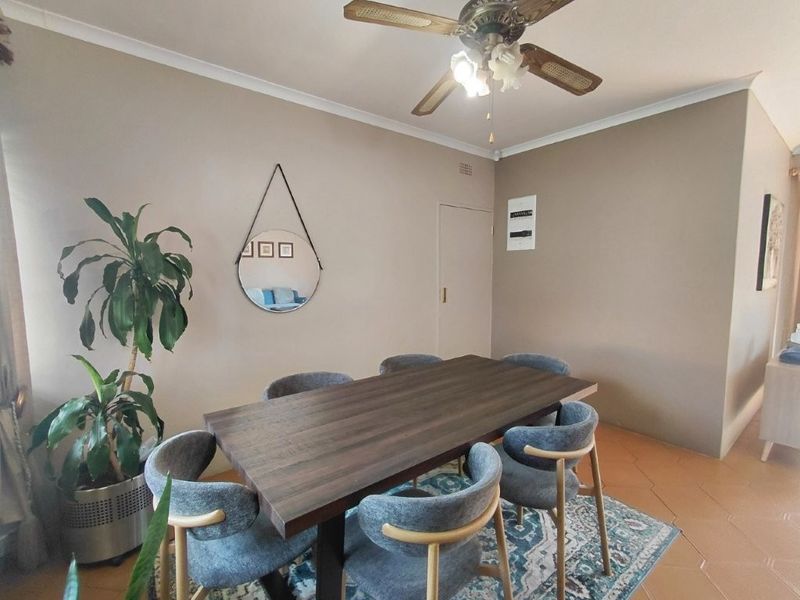 A dining room featuring tiled flooring, a ceiling fan, and neutral wall tones, providing a functional space for family meals.