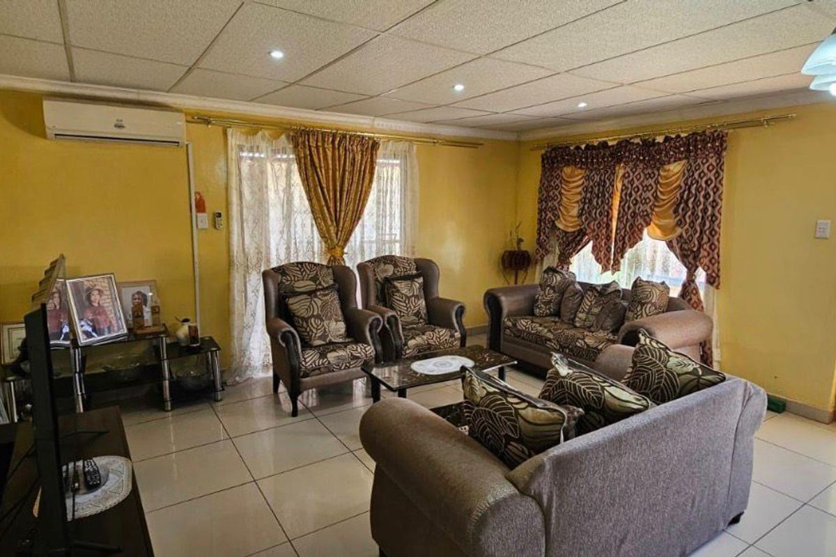 Spacious living room featuring tiled flooring, a split-system air conditioner, and direct access to the garden through a glass panel door.